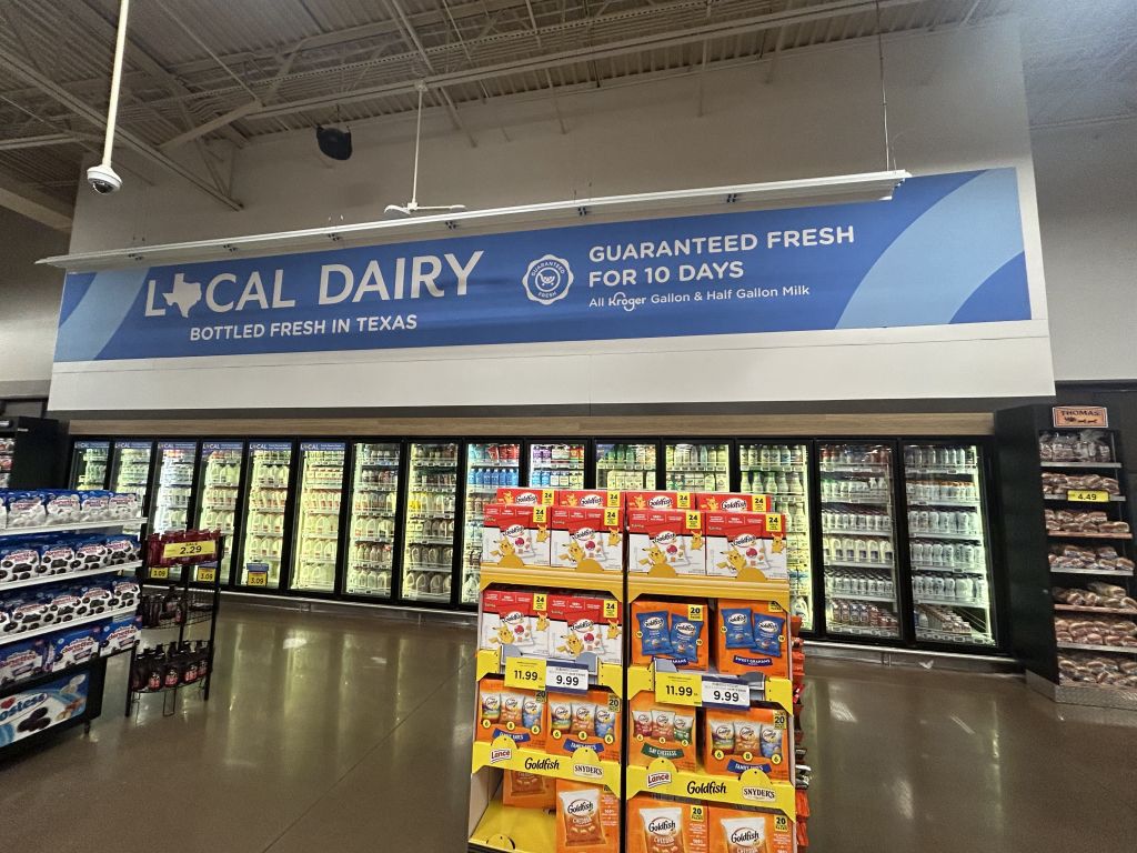 Local dairy overhead banner installed above grocery cooler cases